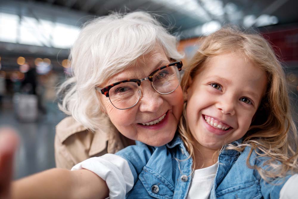 Grandmother and grandchild smiling with bright healthy smiles after Dental Implants in Livonia, MI
