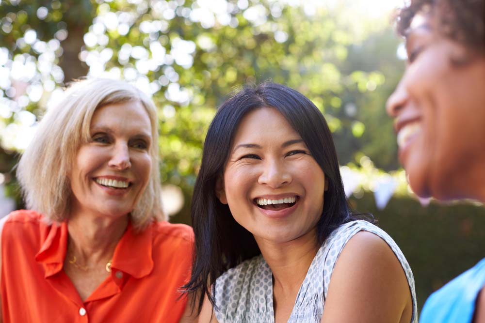 Women smiling outdoors with bright healthy teeth and smiles after Dermal Fillers
