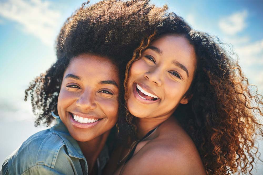 Two women smiling brightly with healthy beautiful smiles after IV Sedation care