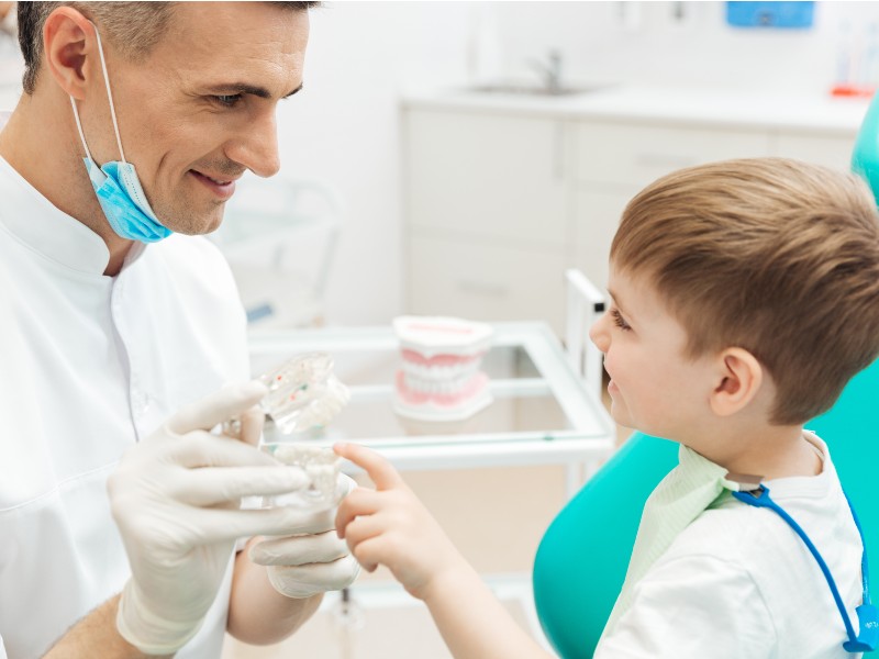 Pediatric dentist helping child feel comfortable during dental visit for Kids Dental Cleaning