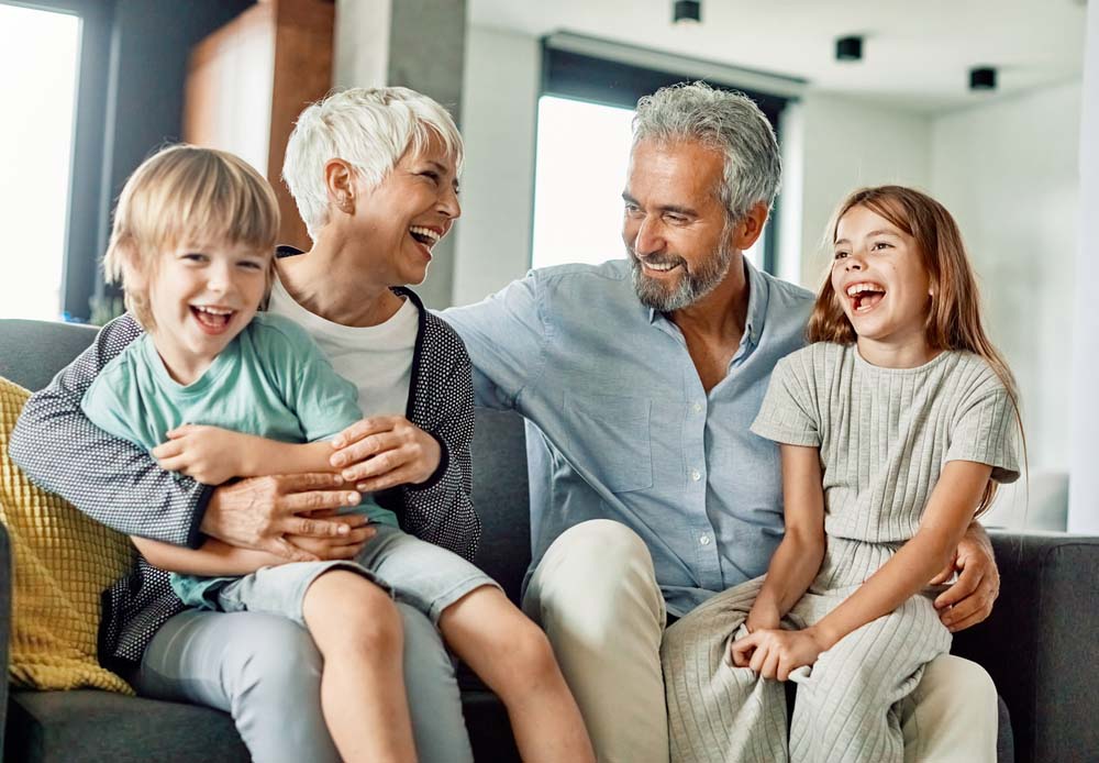 Grandparents and grandchildren laughing together with healthy family smiles