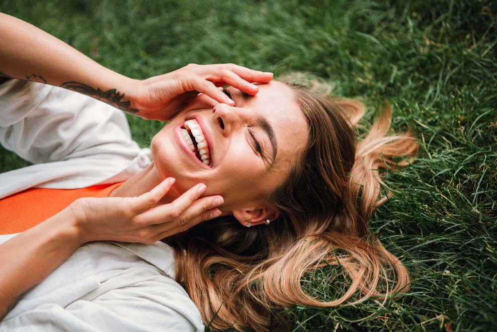 Woman smiling outdoors with a happy smile after TMJ Therapy in Flint, MI