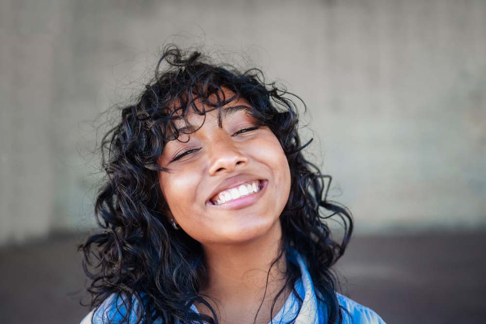 Young woman smiling brightly with healthy white teeth and confident smile after Zoom Whitening